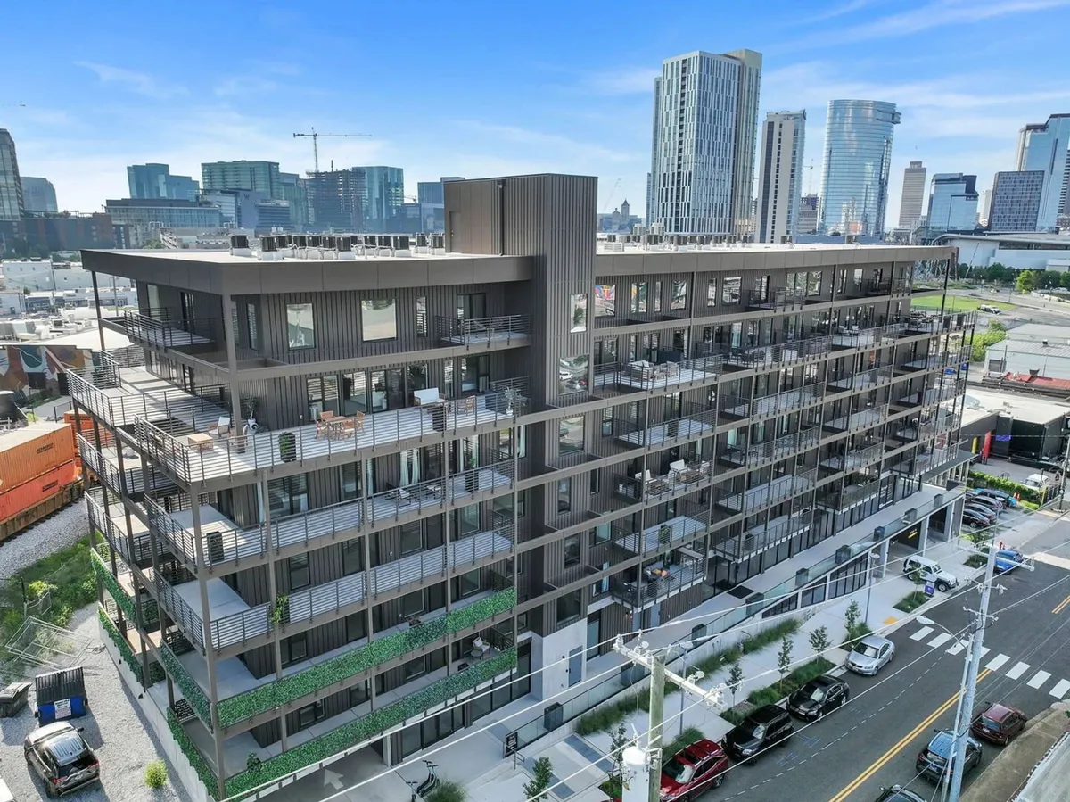 A wide view of the building’s rooftop and balconies, adorned with greenery, overlooking the city skyline. The architectural style is sleek and urban, providing a sense of elevated escape with sweeping panoramic views of downtown Nashville.